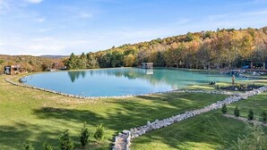 A large, tranquil lake surrounded by a well-maintained lawn and a stone border.