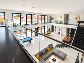 A spacious, multi-level interior with a pool table, seating areas, and a staircase. - Villa Loft - Piscine - Climatisation (Le Cheix-sur-Morge)