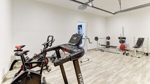Et fitnessrum med træningsudstyr, herunder løbebånd, spinningcykler og styrkemaskiner.