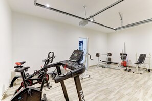 Uma academia com equipamentos de exercícios, incluindo esteira, bicicleta ergométrica e aparelhos de musculação.