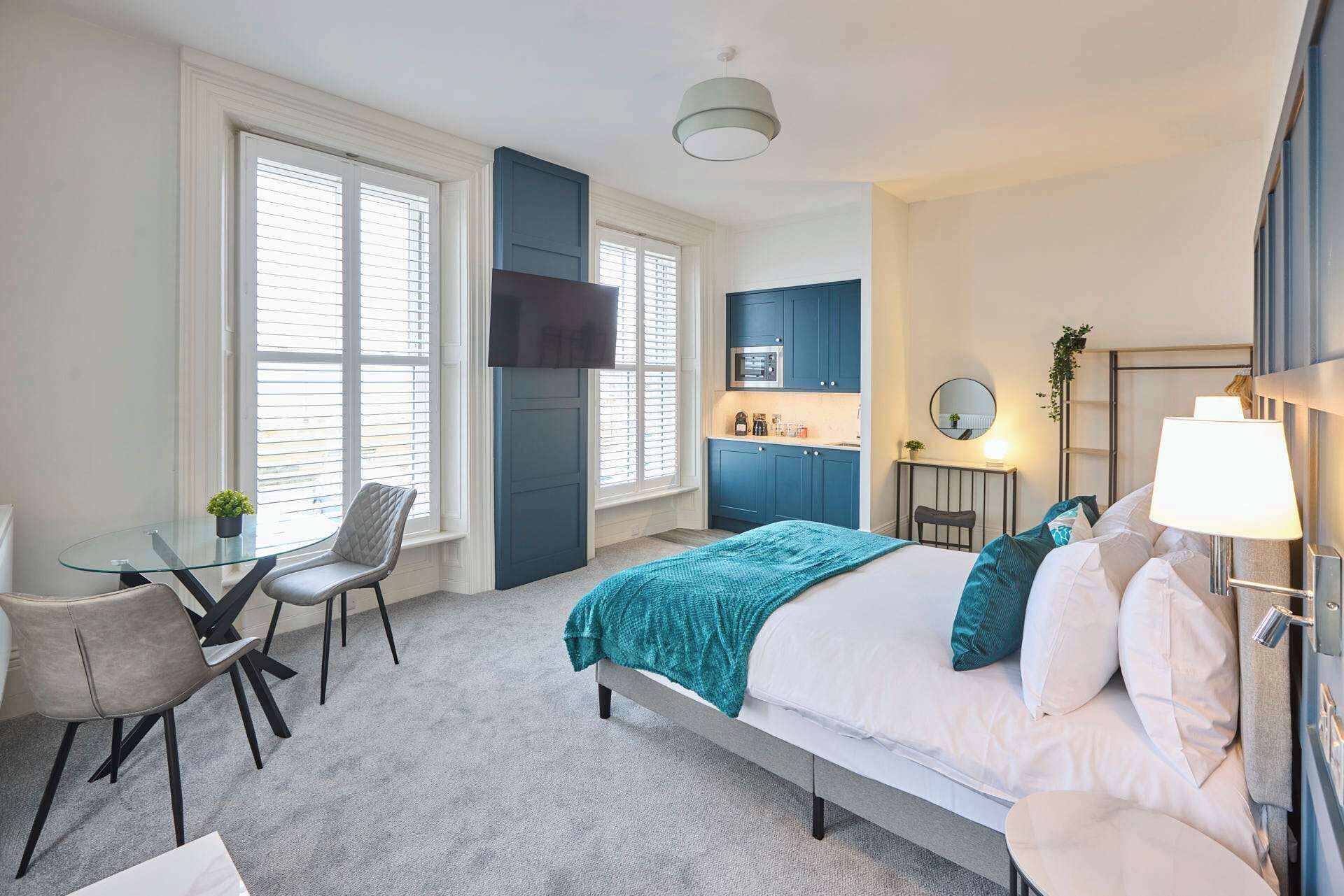 Une chambre comprenant un lit, un bureau, une chaise, une télévision, un coin cuisine et une salle de bain.