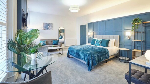 Une chambre moderne avec un lit, un canapé, une table en verre et une chaise.