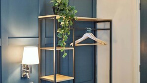 Une étagère en bois fixée au mur, avec une plante suspendue et un cintre en bois.