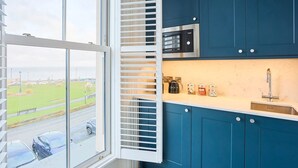 Une cuisine avec des meubles de rangement bleus, un four à micro-ondes, une bouilloire et un évier.