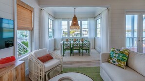 A bright, open-plan living area with a dining table, chairs, and a sofa. - 1 Bedroom Villa - Sunset Point, Abaco -SeaScape Villa # 9 (Elbow cay)