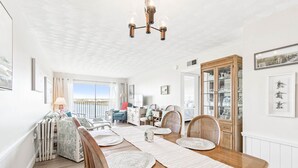 A spacious dining area with a wooden table, woven placemats, and a chandelier. - Charming Waterview Condo | 6 min wlk to beach! (Indian Shores)