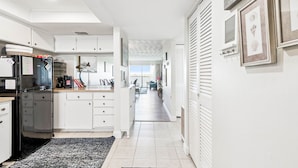A modern kitchen with white cabinets, a black refrigerator, and a dining area with a view. - Charming Waterview Condo | 6 min wlk to beach! (Indian Shores)