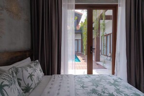 A bedroom with a bed, curtains, and a view of an outdoor pool area. - Chrisenbel Hideaway Retreat, The Villa Collection by Chrisenbel (Petaling Jaya)