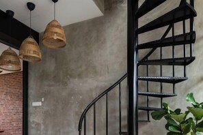 A spiral staircase with wicker pendant lights, a brick wall, and a plant. - Chrisenbel Hideaway Retreat, The Villa Collection by Chrisenbel (Petaling Jaya)