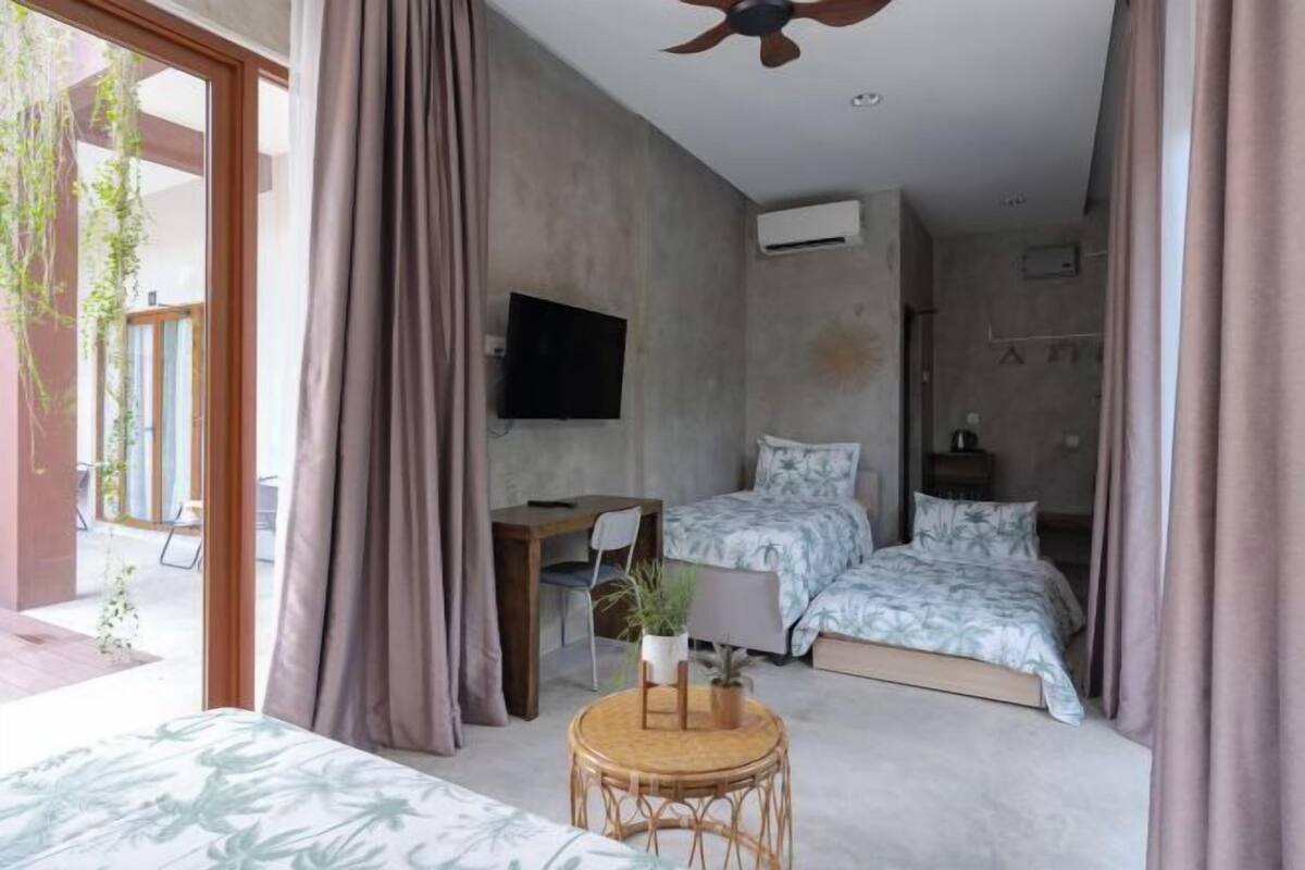 Una habitación de hotel moderna con una cama, un escritorio, una silla, un televisor y una pequeña mesa con una planta.