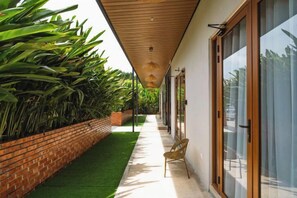 A covered outdoor corridor with a brick wall, green artificial turf, and a chair. - Chrisenbel Hideaway Retreat, The Villa Collection by Chrisenbel (Petaling Jaya)