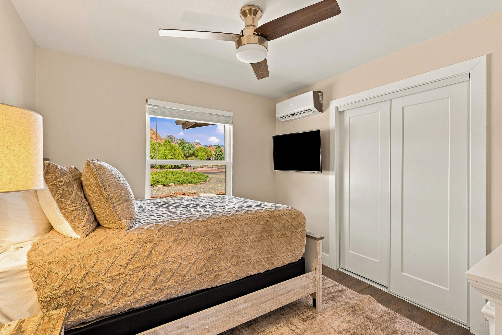 Une chambre avec un lit, un ventilateur de plafond, une fenêtre avec vue, un climatiseur et un téléviseur.