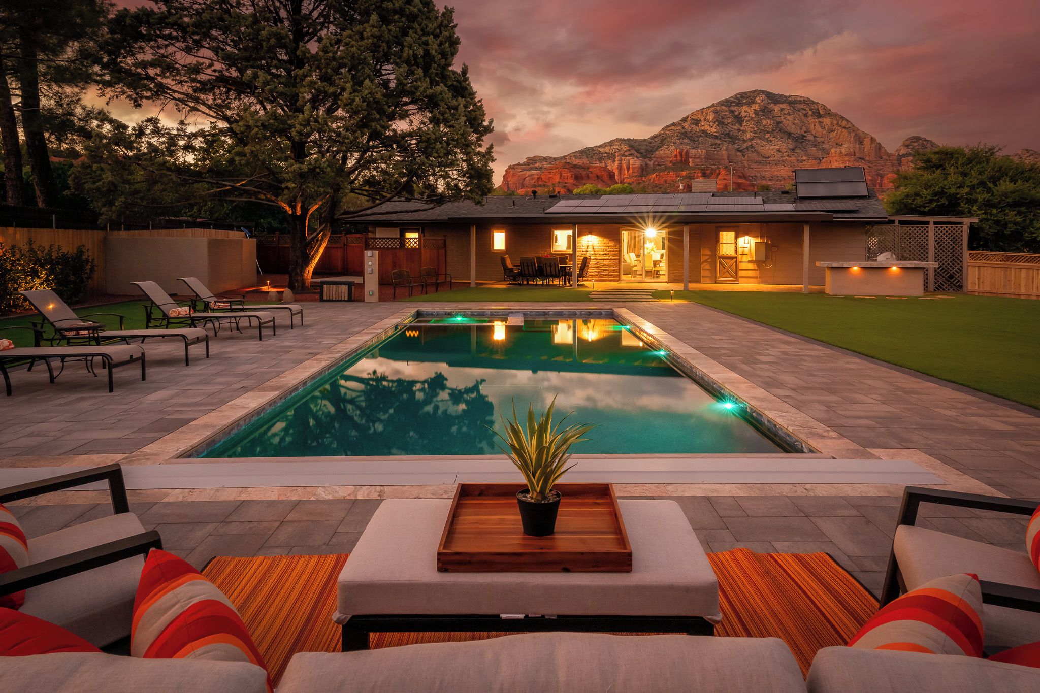 A swimming pool with a patio area, outdoor furniture, and a view of a mountain range.