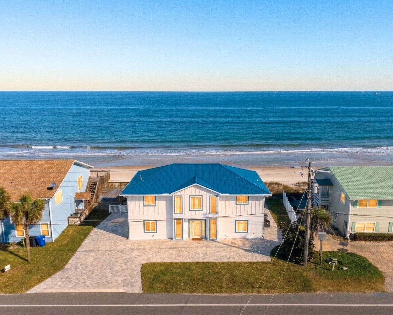 A beachfront property with a large house, a smaller building, and a sandy beach.