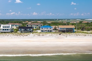 Eigendommen aan het strand met uitzicht op de oceaan, een zandstrand en een heldere lucht.