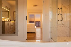 Quarto de hotel com cama, banheiro com chuveiro e vista para o exterior.