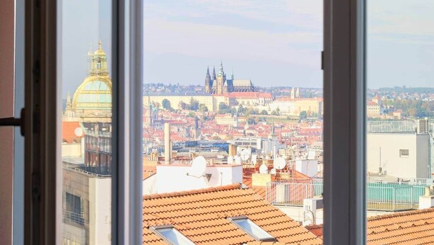 A view through a window of a cityscape with prominent historical architecture, including a large domed building and spires. - Castle View | Terrace | Center - 150m Penthouse (Prague)
