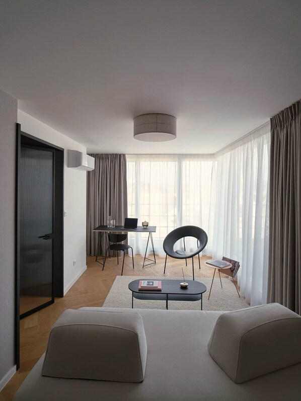 Una habitación de hotel moderna con una cama grande, un escritorio con una computadora portátil, una silla y una pequeña mesa con un libro.