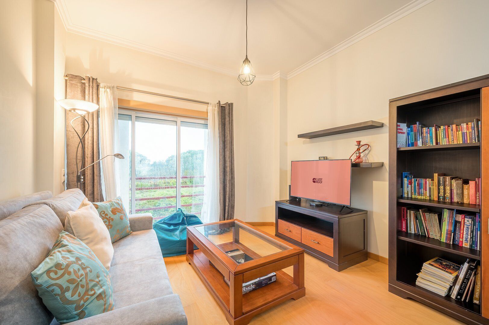 A living room with a sofa, coffee table, bookshelf, and a television.