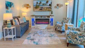 A living room with a fireplace, a sofa, armchairs, a coffee table, and a TV. - Rest & Relax - Beachfront Resort (Myrtle Beach)