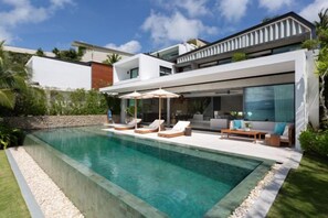 A modern house with a swimming pool, outdoor seating, and a large window overlooking the pool. - Syrah 3-Bedroom Beachfront Villa in Koh Samui (Koh Samui)