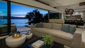 Un salon moderne avec un grand canapé, une table basse et une vue sur l’océan.