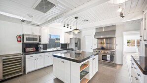 Una cocina moderna con armarios blancos, electrodomésticos de acero inoxidable y una isla central.