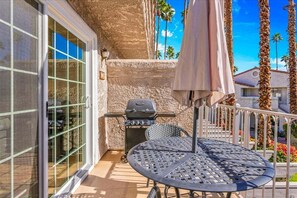 A patio with a grill, a table, and an umbrella. - Sunset Vista Retreat (Palm Springs)