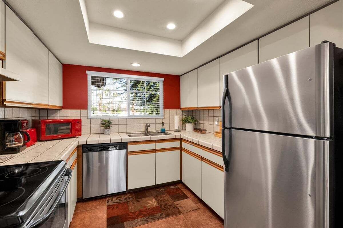 A compact kitchen with a stainless steel refrigerator, a microwave, a stove, and a dishwasher.