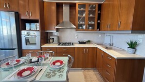 Una cocina moderna con armarios de madera, electrodomésticos de acero inoxidable y una zona de comedor preparada para cuatro personas.