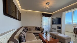 Una sala de estar moderna con un sofá modular, una mesa de centro de vidrio y vistas al exterior.