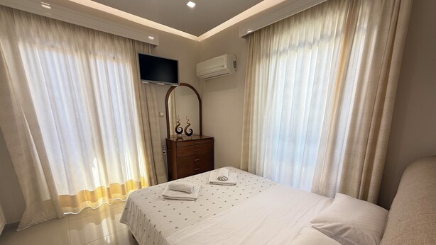 Una habitación de hotel con cama, cómoda, televisor y aire acondicionado.