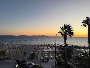 A beachside promenade with outdoor seating and a view of the sea at sunset. - Anna’s Seaside Apartment - In front of the beach (Kos)