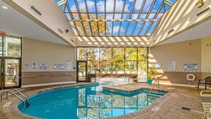 An indoor swimming pool with a glass ceiling, surrounded by brick flooring, and equipped with safety signs. - Sun & Fun - Rest & Relax (Myrtle Beach)