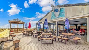 An outdoor deck with picnic tables and umbrellas, a wooden gazebo, and a mural on the building. - Sun & Fun - Rest & Relax (Myrtle Beach)