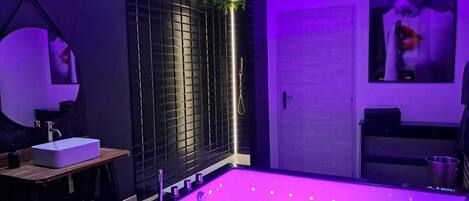 A modern bathroom with a large bathtub, a sink, and a shower area.