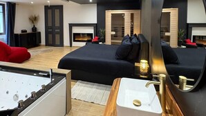 Een moderne slaapkamer met een groot bed, een houten kaptafel, een whirlpool en een grote spiegel.