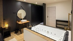 Een moderne badkamer met een vrijstaand bad, een ronde spiegel en een klein houten wastafelmeubel.