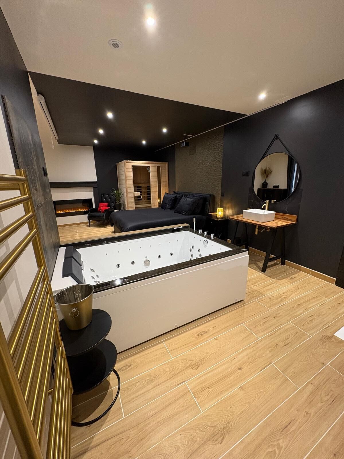 Een moderne slaapkamer met een groot bad, een zwarte bank en een houten vloer.
