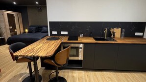 Een moderne keuken met een houten tafel en stoelen, een inbouwoven en een zwarte spatwand.