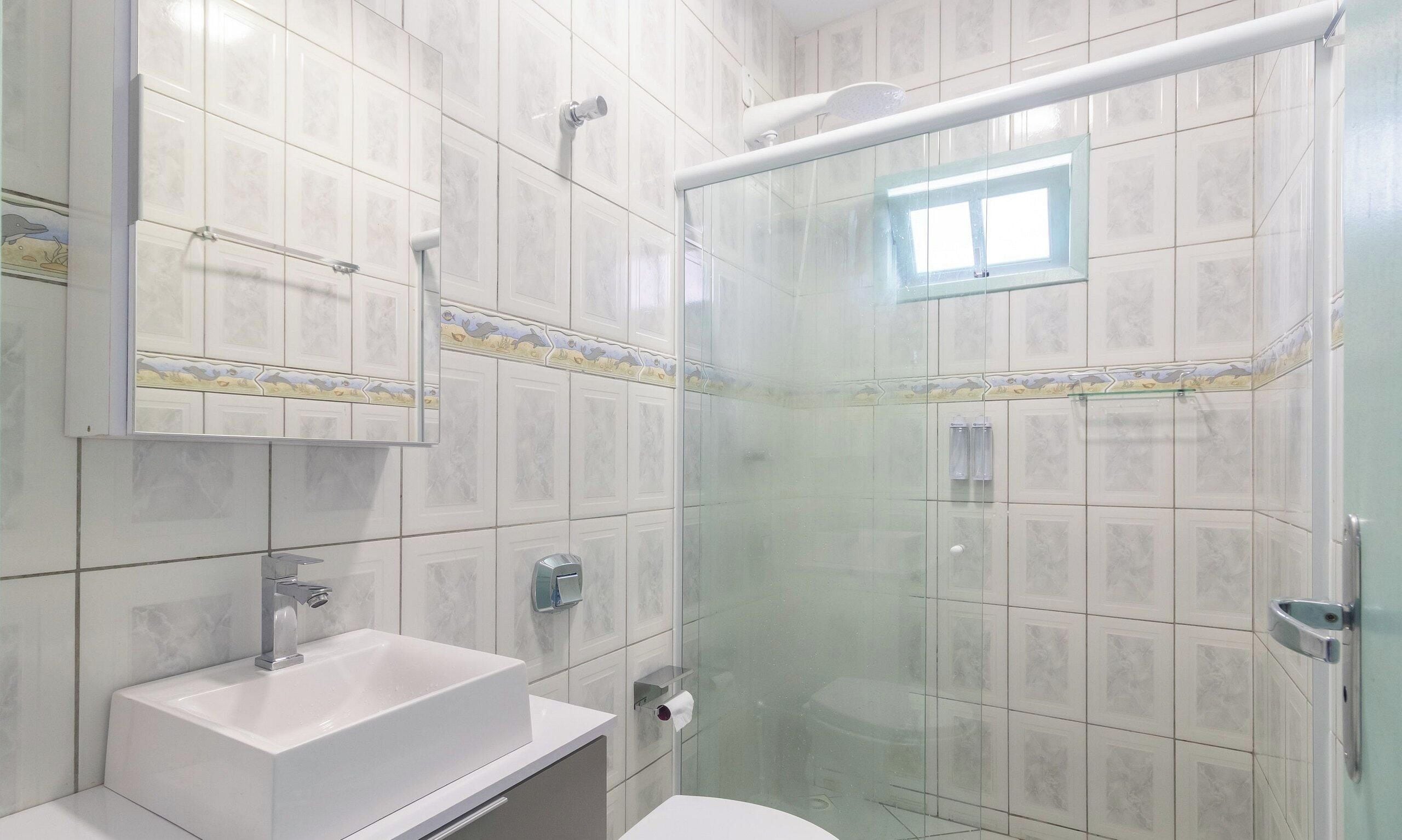 A bathroom with a glass shower enclosure, a sink, and a mirror.