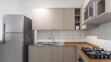 A modern kitchen with a stainless steel refrigerator, a gas stove, and a sink with a faucet.