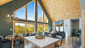 Une cuisine spacieuse, dotée de grandes fenêtres, d’un plafond en bois et d’un îlot central.