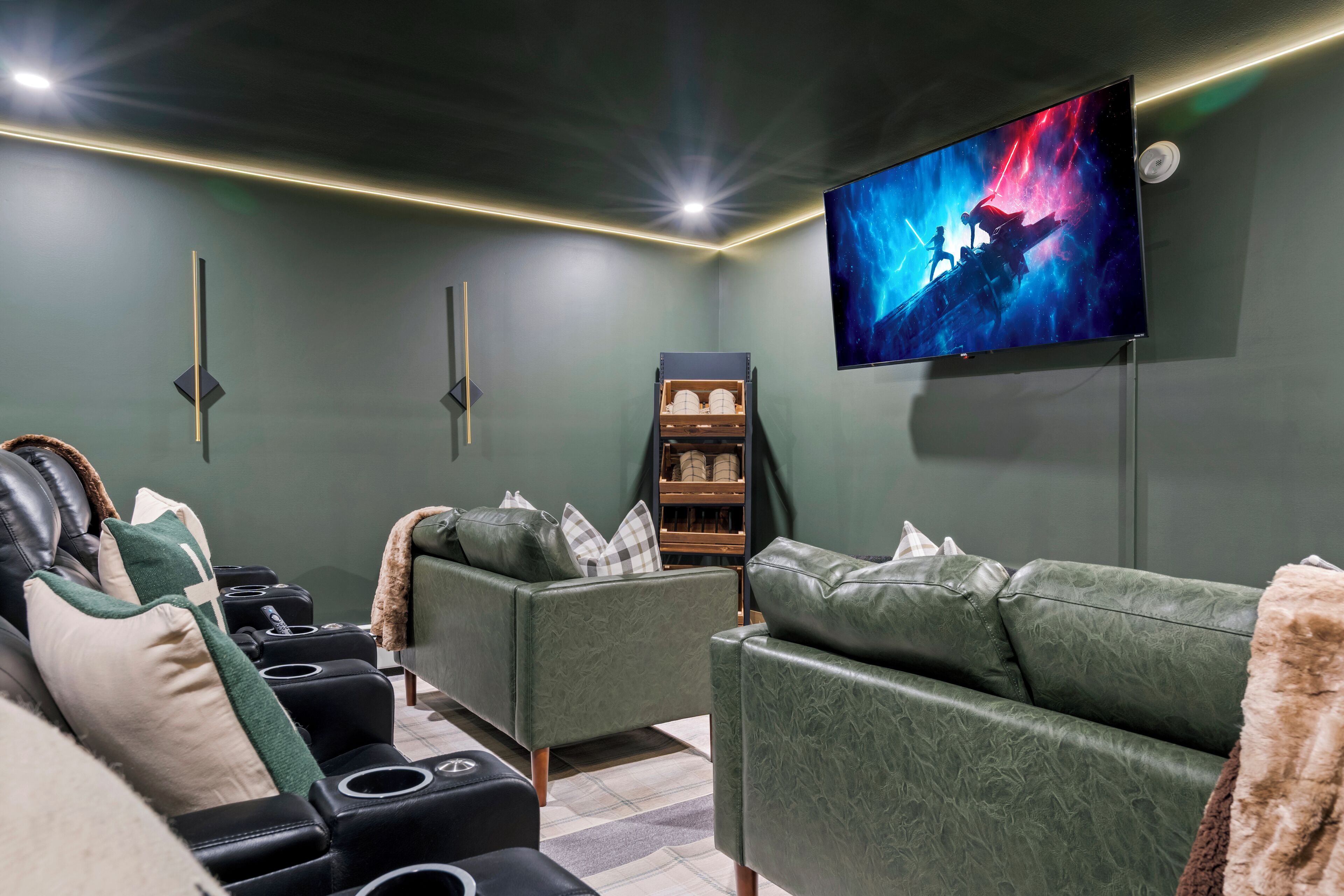 Uma sala de cinema com uma TV de tela grande, sofás de couro verde e uma barra de som.