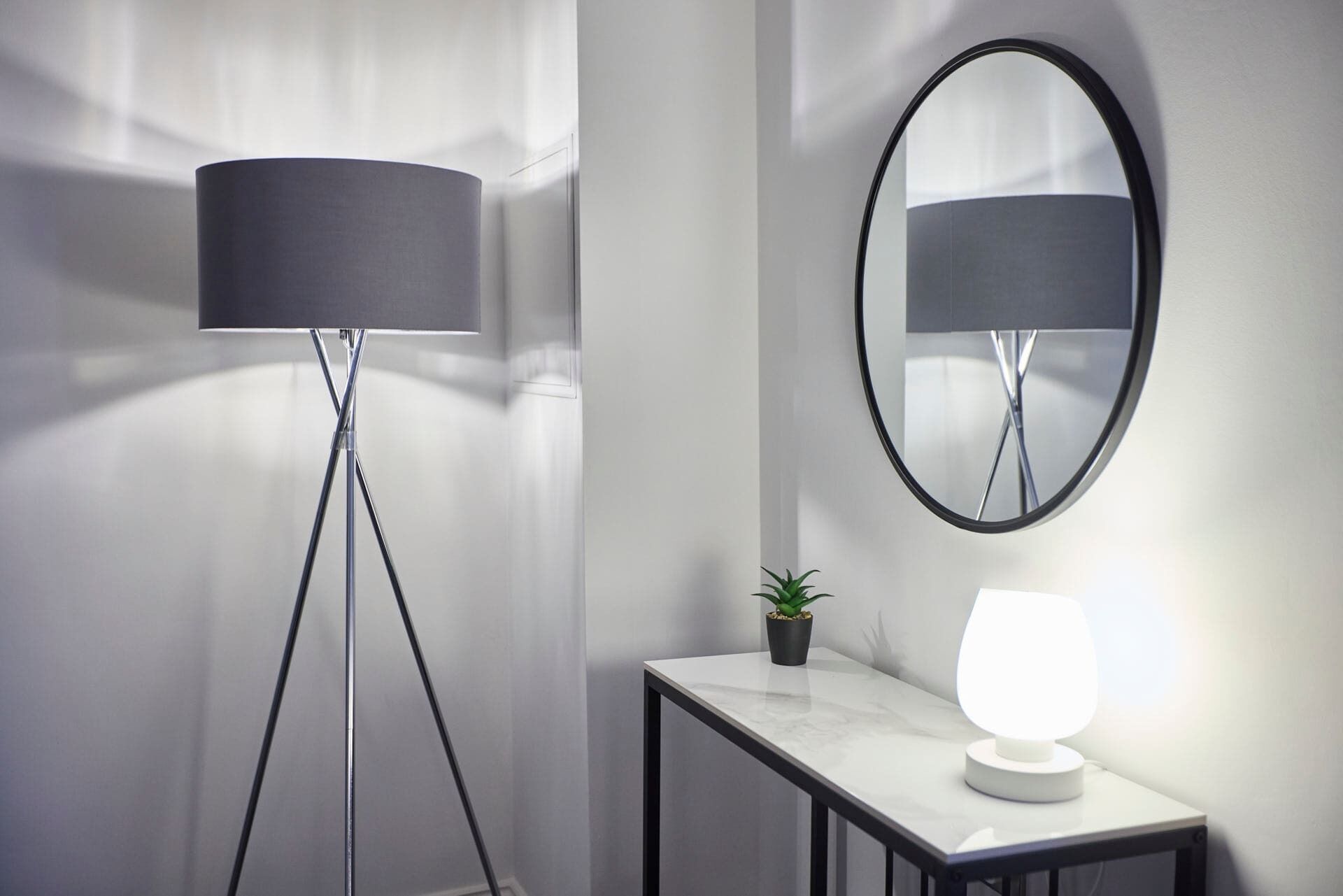 A modern room with a floor lamp, a table with a lamp, and a mirror on the wall.