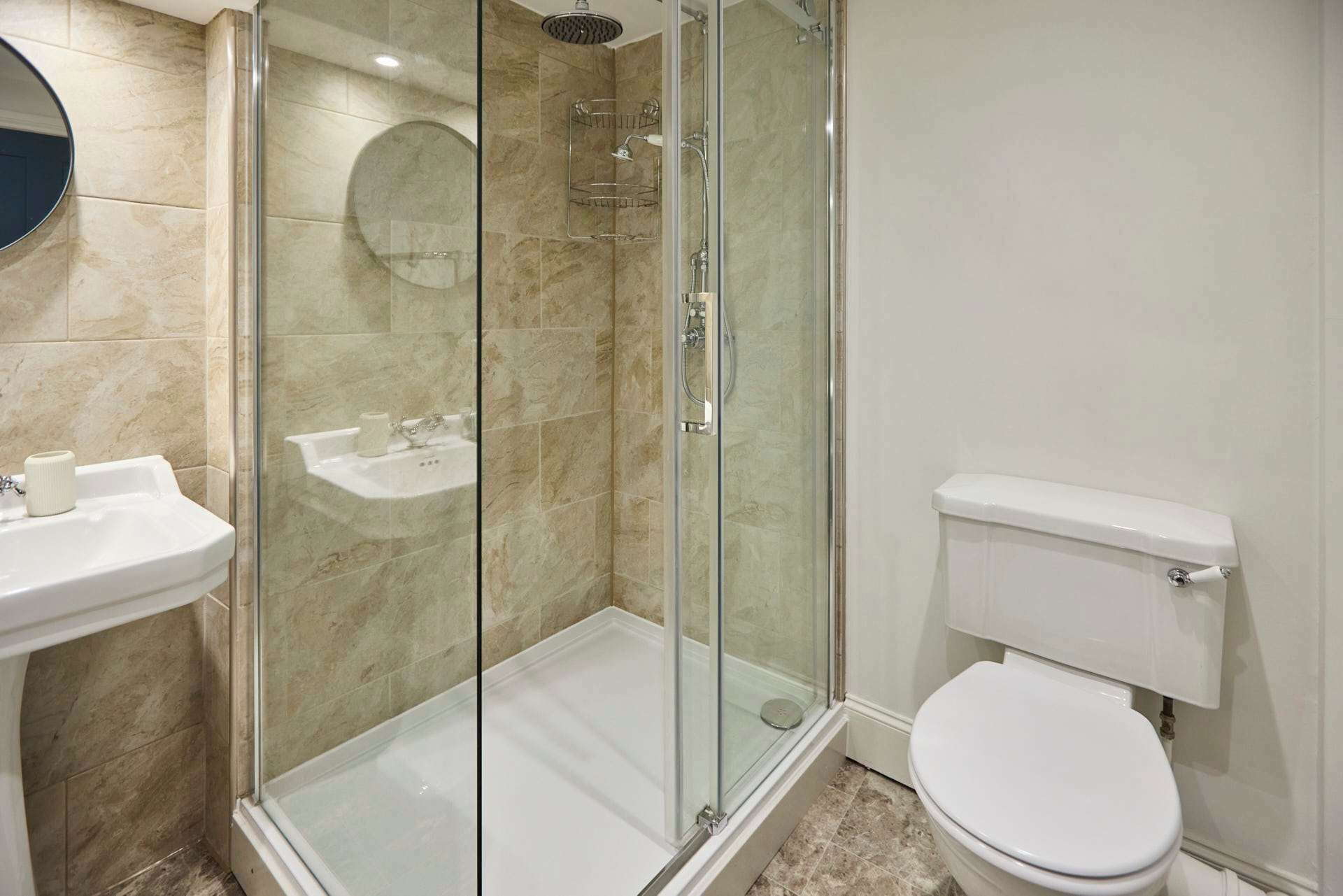 A modern bathroom with a glass-enclosed shower, a white sink, and a toilet.