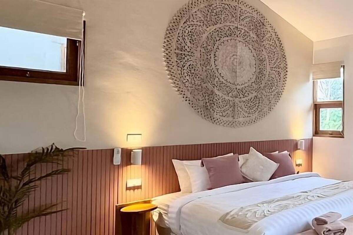 Une chambre d’hôtel avec un lit, des éléments de décoration murale, des lampes de chevet et une fenêtre.