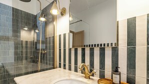 Ein Badezimmer mit Marmorwaschbecken, goldenem Wasserhahn und einer Holztablett.