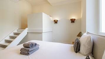 Een hotelkamer met een bed, een trap, een wandlamp en een raam.