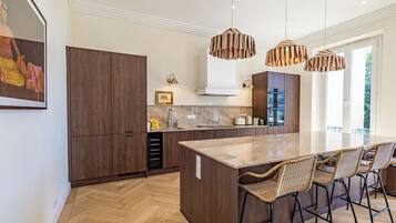 Een moderne keuken met een groot schiereiland, houten keukenkastjes en hangende lampen.